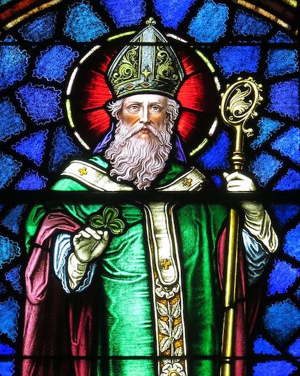 Colourful stained glass window showing St Patrick dressed in a green rove